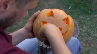 Adam bir kabak Jack-o-fener bahçede bir ağaç kütüğü üzerinden açmaktadır