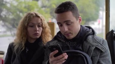 Genç adam ve Gadget'ları hakkında sohbet ve bir şey online paylaşım Tramvayda oturan kadın