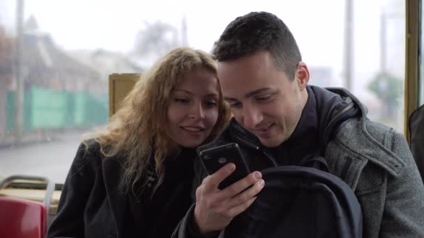 Jeune homme et femme assis dans le tram bavarder sur les gadgets et partager quelque chose en ligne — Video