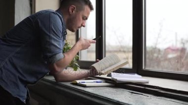 Genç adam öğrenci kitap smartphone cep telefonu ile fotoğraf yapıyor orta çekim