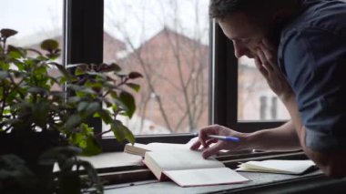 Pan gencin ayakta pencerenin yakınındaki okurken telefonda konuşuyor