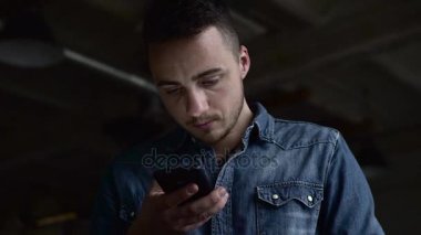 Genç bir adam düşük açılı büyük bir karanlık salonda telefon kullanma