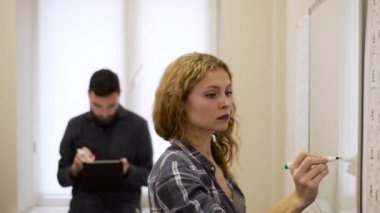 İş kadını orta çekim bir işaretleyici bir marker ile bir beyaz tahtaya çizer.