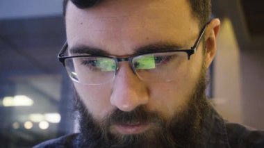 Bir Tablet üzerinde çalışan Cafe oturan gözlüklü genç sakallı bir adam portresi