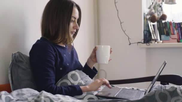 ノート パソコンを自宅で彼女のベッドの上の若い女性 — ストック動画