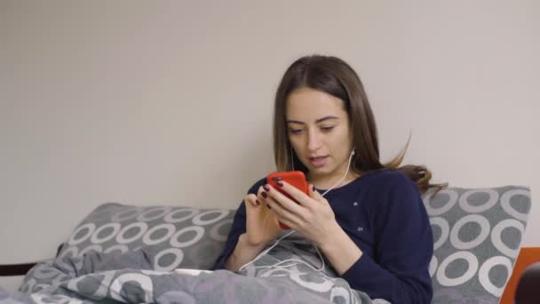 Красивая женщина слушает музыку в наушниках на мобильном телефоне — стоковое видео
