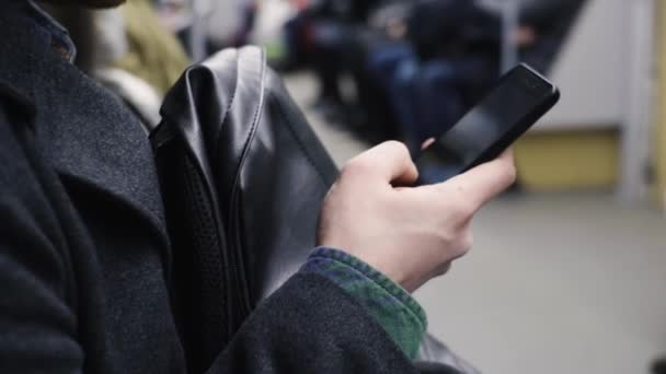 Ung man rider ett metro tåg och använder sin mobiltelefon — Stockvideo