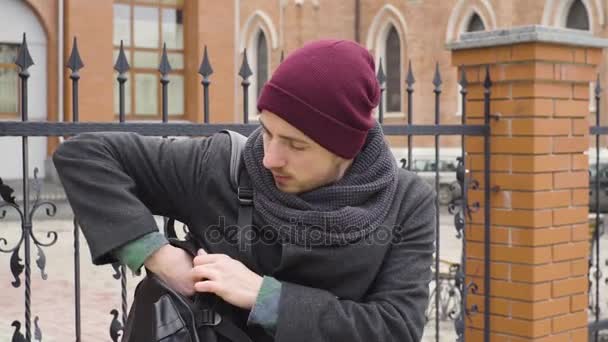 Ein junger Mann benutzt in der Stadt gegenüber der Kirche eine Tablette — Stockvideo