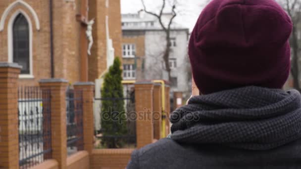 Молодой человек фотографирует церковь с табличкой — стоковое видео