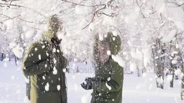 A fióktelep a hó esik. Egy pár kiterjed a fejét, kapucnival. Lassú mozgás — Stock videók