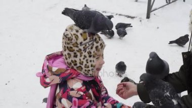 Anne ve kızı bir kış parkta güvercin besleme
