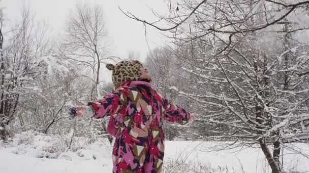 Een klein meisje staat onder een lawine van sneeuw — Stockvideo