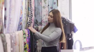 Genç güzel kadın kumaş Tekstil dükkanda seçer.