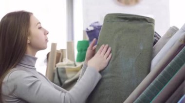 Genç güzel kadın kumaş Tekstil dükkanda seçer.
