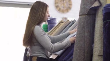 Genç güzel kadın kumaş Tekstil dükkanda seçer.