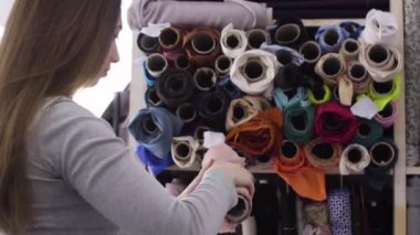 Genç güzel kadın kumaş Tekstil dükkanda seçer.