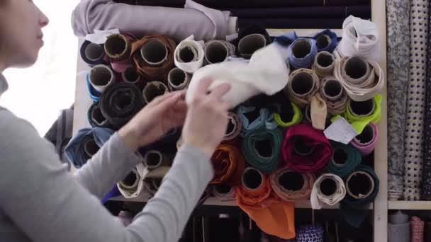 Joven hermosa mujer elige la tela en una tienda textil — Vídeo de stock