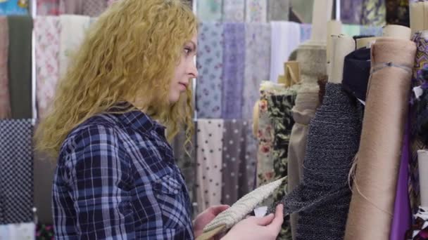 Ung vacker kvinna väljer tyget i en textilbutik — Stockvideo