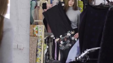 Genç bir kız için bir elbise bir ayna yakınındaki bir bez içinde atelier seçer.