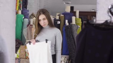 Genç bir kız için bir elbise bir ayna yakınındaki bir bez içinde atelier seçer.
