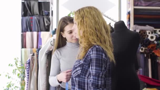 Joven costurera tomando medidas de cliente femenino — Vídeos de Stock