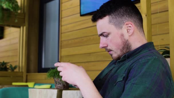 Primer plano del hombre utilizando el teléfono inteligente en la cafetería — Vídeos de Stock