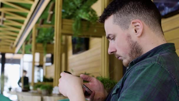 Primer plano del hombre utilizando el teléfono inteligente en la cafetería — Vídeos de Stock