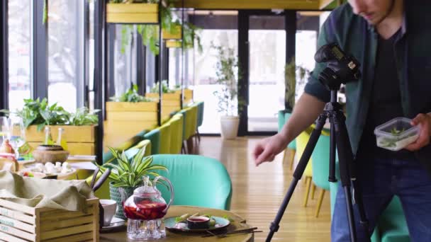 Trípode de disparo del hombre utilizando la cámara digital y hacer fotos de alimentos en la mesa de madera — Vídeo de stock