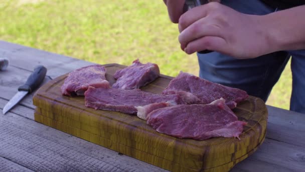 Männer salzen und pfeffern das Fleisch. Vorbereitungen für ein Grillfest. — Stockvideo