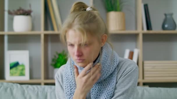 En sjuk flicka hostar på en soffa i vardagsrummet — Stockvideo