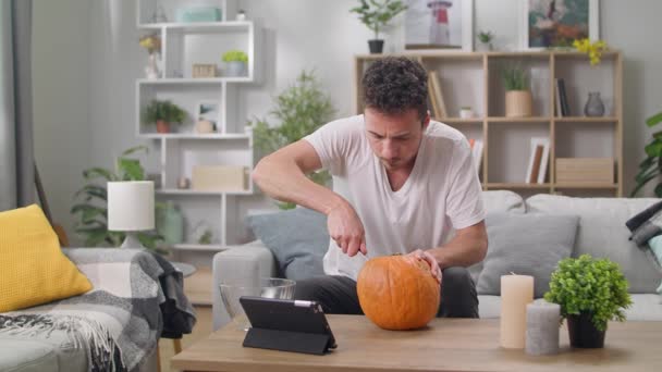 Young man watches online lesson how to carve Jack the Lantern — ストック動画