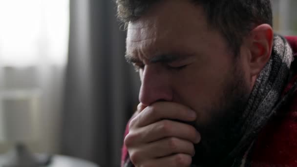 Un homme tousse lourdement alors qu'il est assis sur un canapé dans le salon — Video