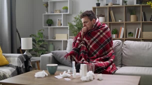Muž těžce kašle, zatímco sedí na pohovce v obýváku — Stock video