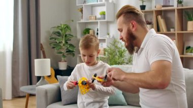 Baba ve oğul oturma odasında bir çocuk tasarımcısıyla oynuyorlar.