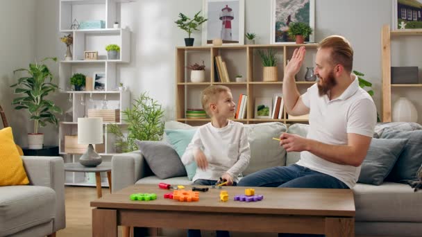 Πατέρας και γιος παίζουν με έναν σχεδιαστή παιδιών στο σαλόνι. — Αρχείο Βίντεο