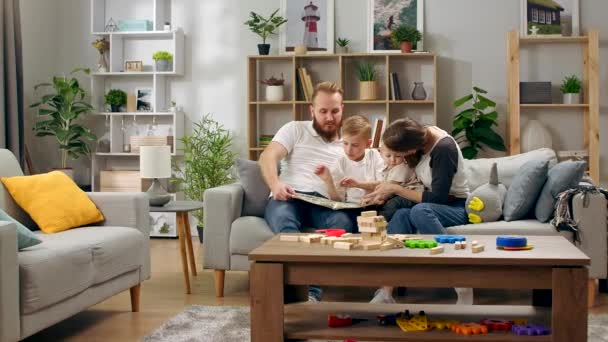 Lycklig familj läser en bok på soffan — Stockvideo