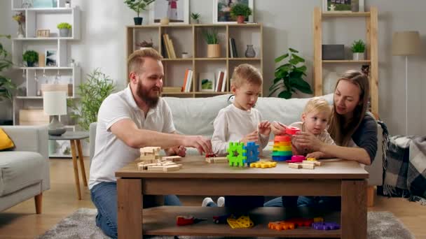 Familia feliz jugando con juguetes sobre la mesa en la sala de estar — Vídeos de Stock