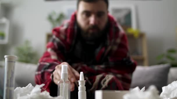 Ill man uses nasal spray on sofa in living room — ストック動画