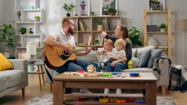Babam gitar çalıyor ve tüm aile eğlenceli bir şarkı söylüyor.