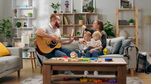 O pai toca guitarra e toda a família canta uma música divertida. — Vídeo de Stock