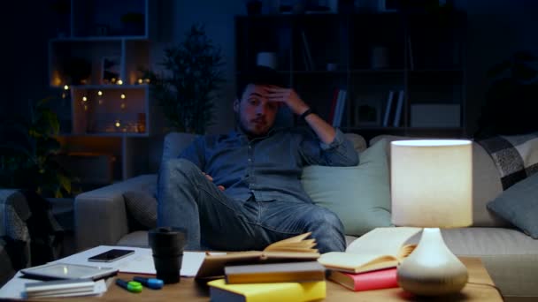 El joven está cansado, pero sigue estudiando en casa por la noche. . — Vídeos de Stock