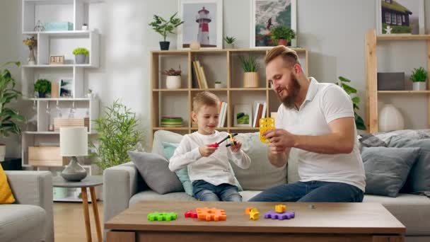 Ojciec i syn bawią się z konstruktorem w salonie — Wideo stockowe