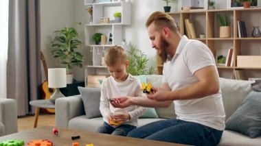 Baba ve oğul oturma odasında bir çocuk tasarımcısıyla oynuyorlar.