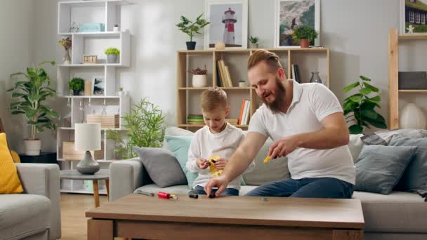 Father and son play with a children s designer in the living room — Stock Video