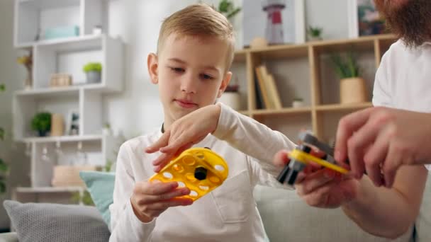 Padre e hijo juegan con un diseñador infantil en la sala de estar — Vídeo de stock