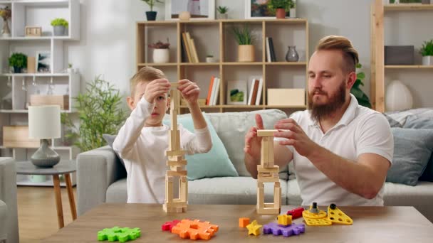 父亲和儿子在客厅里用木块建造塔楼 — 图库视频影像