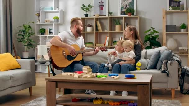O pai toca guitarra e toda a família canta uma música divertida. — Vídeo de Stock