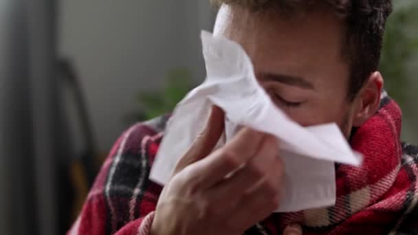 Den sjuke mannen blåser näsan i en servett i vardagsrummet. — Stockvideo