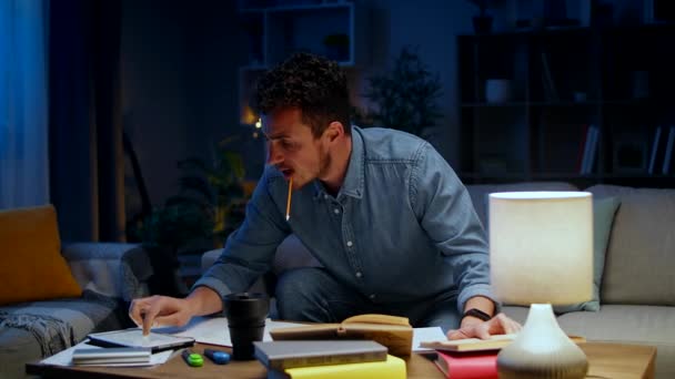 Giovane uomo usa un tablet mentre studia a casa la sera — Video Stock