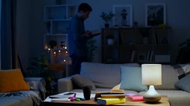 Genç adam gece evde çalışırken bir kitap okur..